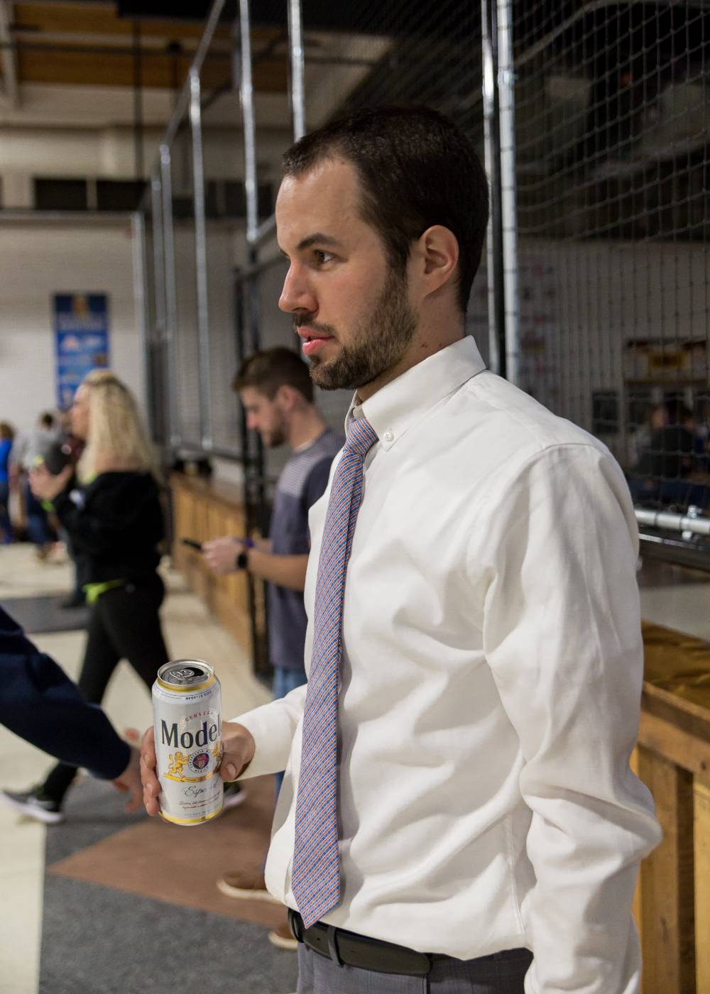 An alumnus holding a drink, watching the game at the Fowling Fun Event
